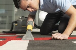 Carpet cleaning technician using hot water extraction equipment to remove stains and allergens